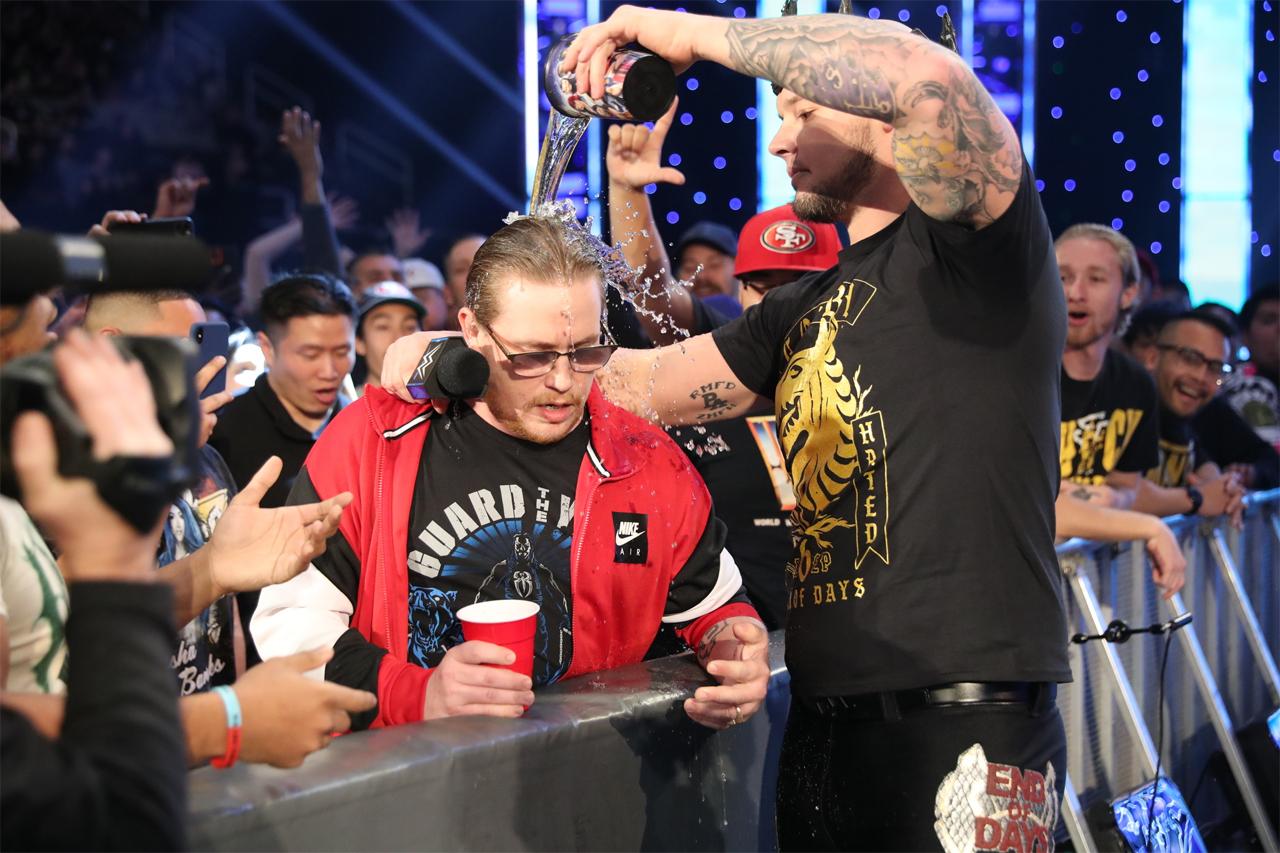 WWE superstar Baron Corbin playfully pours some beverage on a WWE fan at ringside.
