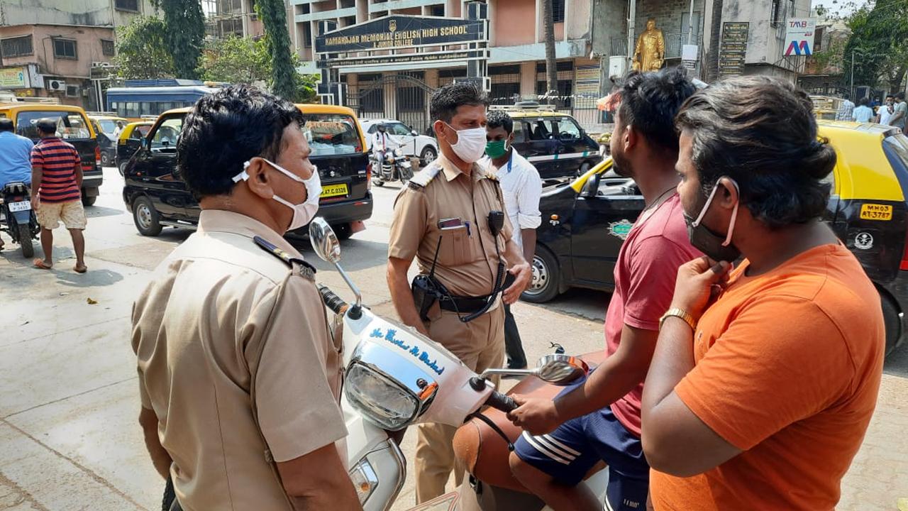 Officials of the Mumbai Police impose fines on people roaming without a mask in Dharavi after Mumbai and Maharashtra started witnessing an increase in the number of COVID-19 cases post-February 2021. Pic/Pradeep Dhivar