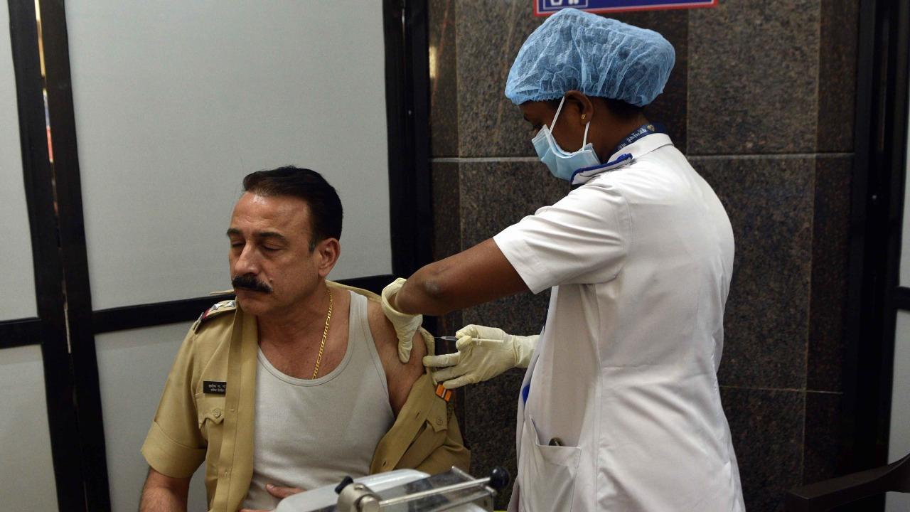 A police officer without a face mask gets vaccinated at Bharatratna Dr. Babasaheb Ambedkar Municipal General Hospital, Kandivli.