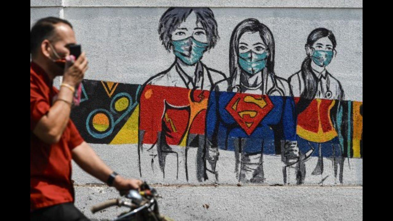 A man cycles past a wall mural depicting health workers as superheroes amidst rising Covid-19 coronavirus cases, in Mumbai on March 29, 2021.
Photo: AFP