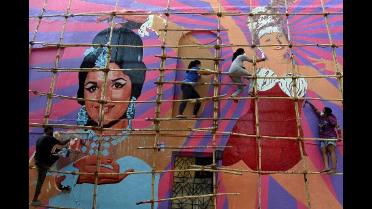 Artists paint a wall mural of Bollywood actresses Asha Parekh (left) and Helen (right) on a residential building in Mumbai on May 14. Photo: AFP