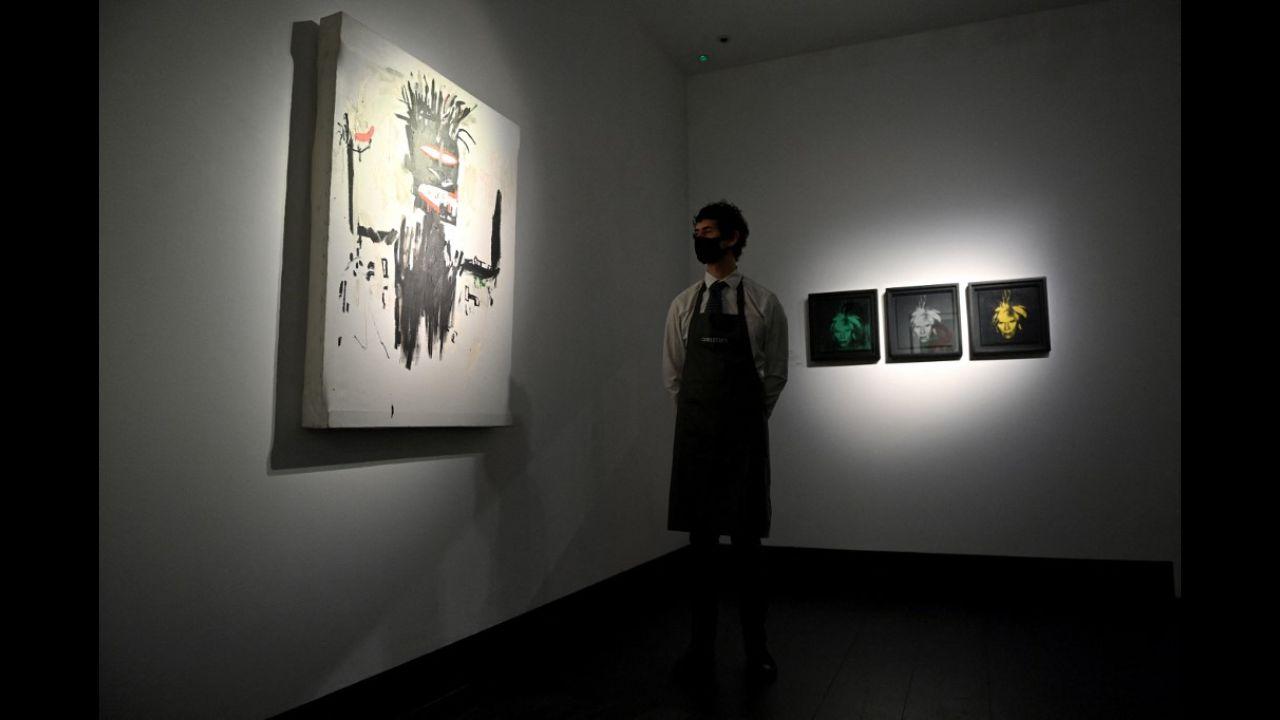 A gallery worker stands alongside an artwork titled 'Self Portrait' by American artist Jean Michel Basquiat (L) and the artwork 'Three Self-Portraits' by American artist Andy Warhol at Christie’s auction house in central London on March 16, 2021.
Photo: Justin Tallis / AFP