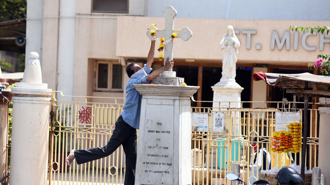 Adjusting the garland: On Good Friday, a man tries to adorn the pillar outside St. Michael's church in Mahim with a garland. Pic: Sameer Markande