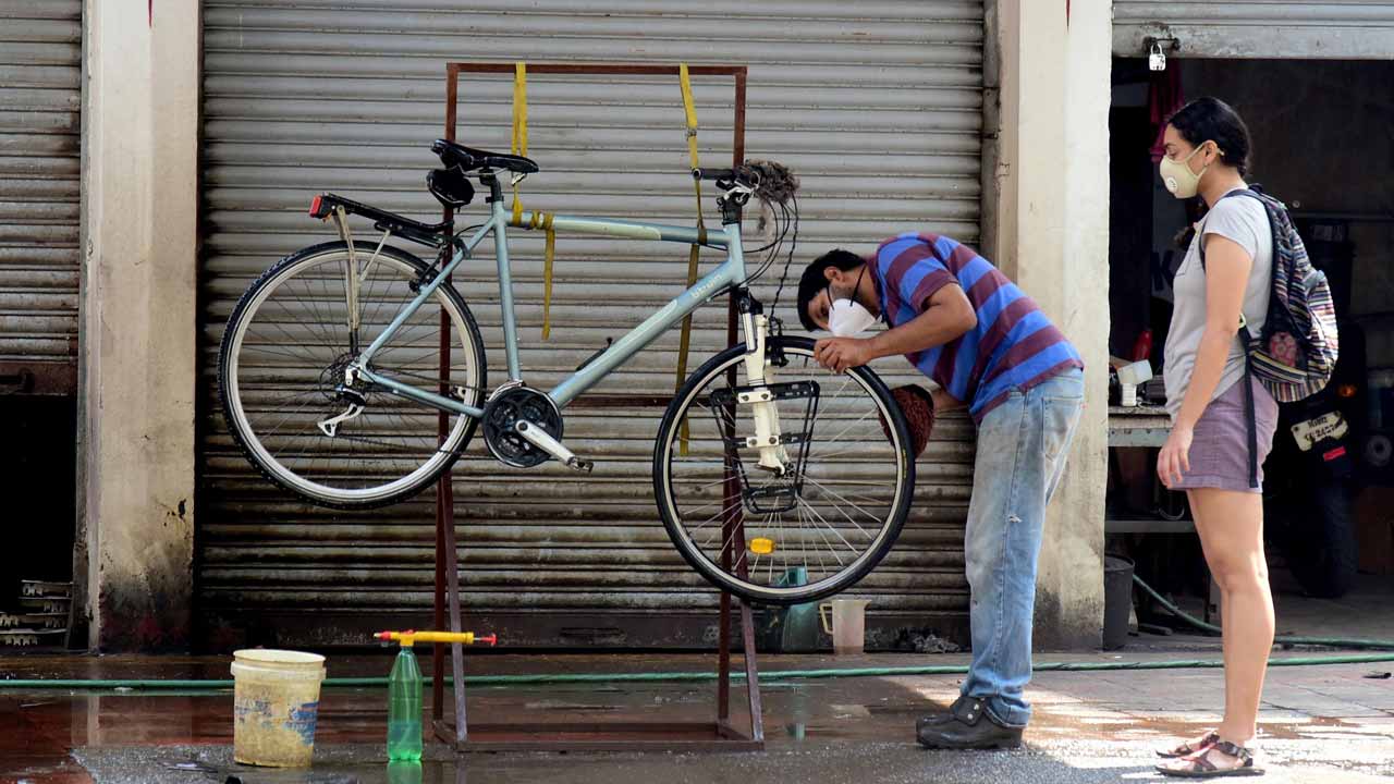 A cyclist gets her bicycle washed and serviced at a motor car service centre at Ballard Estate in South Mumbai. Photo: Suresh Karkera