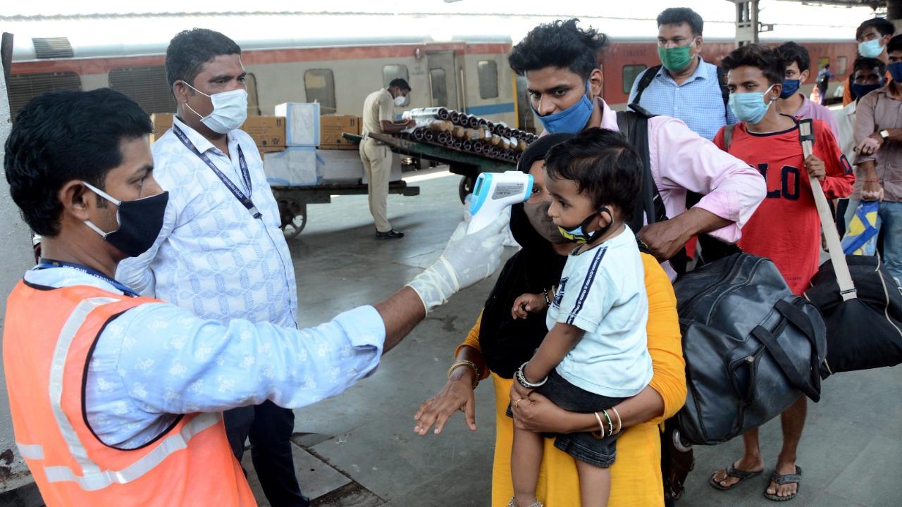 In picture: A healthcare worker checks the body temperature of passengers arriving at Lokmanya Tilak Terminus (LTT) railway station in Kurla. Photo: Sameer Abedi