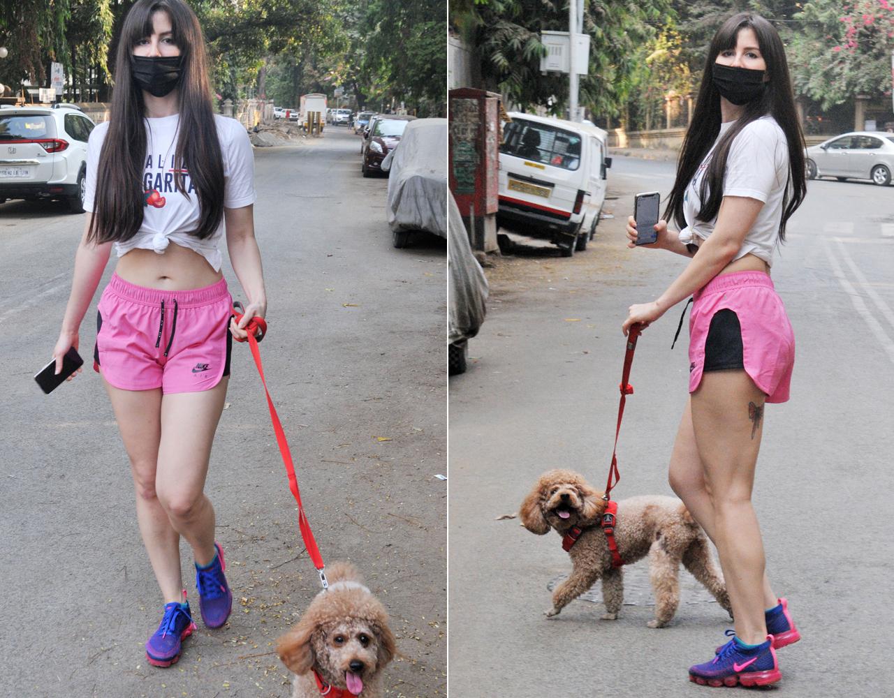 Giorgia Andriani was snapped as she was taking a stroll with her pet on the streets of Bandra, Mumbai. The model-actress looked stunning in a white t-shirt, pink shorts and blue running shoes.