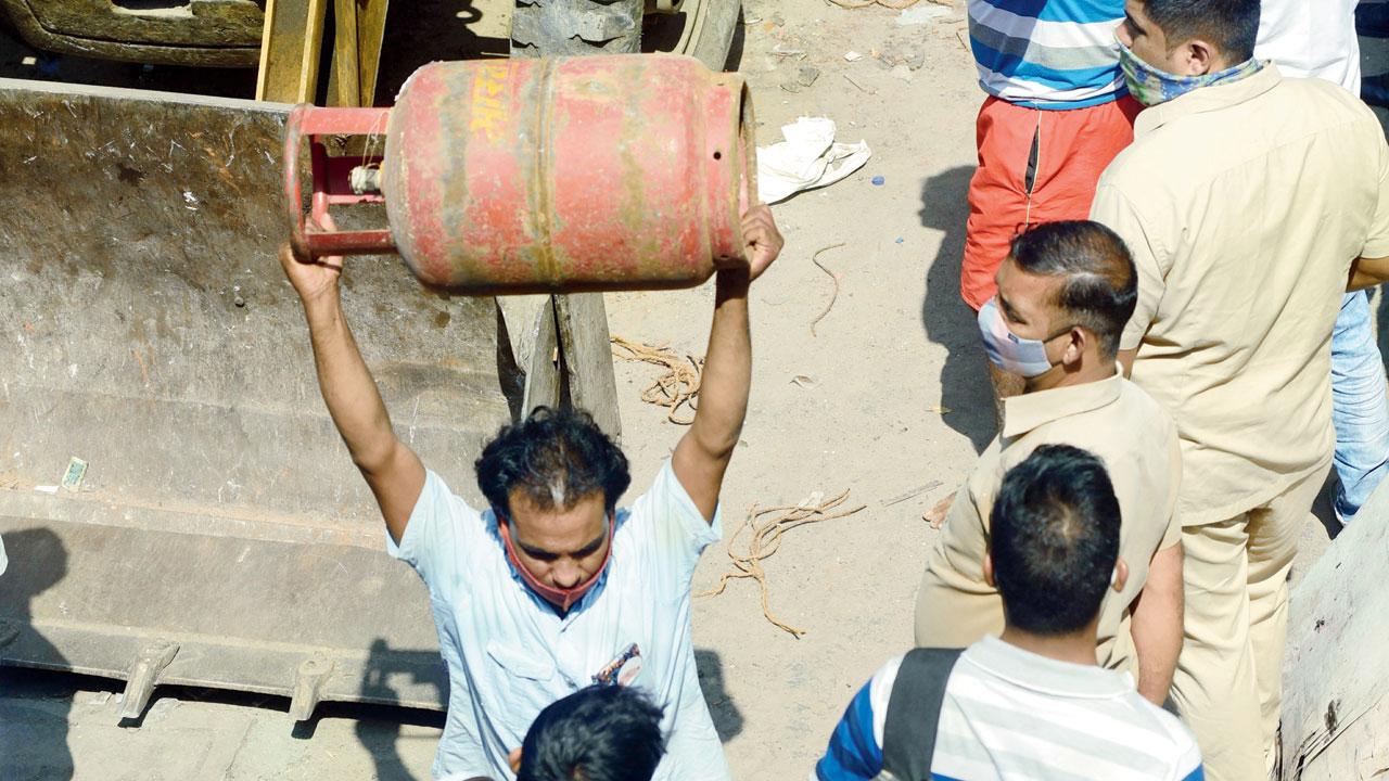 A man carries a gas cylinder out of one of the collapsed houses