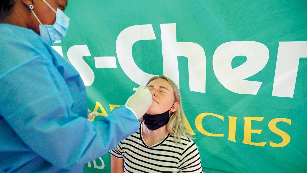 A healthcare worker conducts a COVID-19 test on a traveller at OR Tambo International Airport in Johannesburg on Saturday.