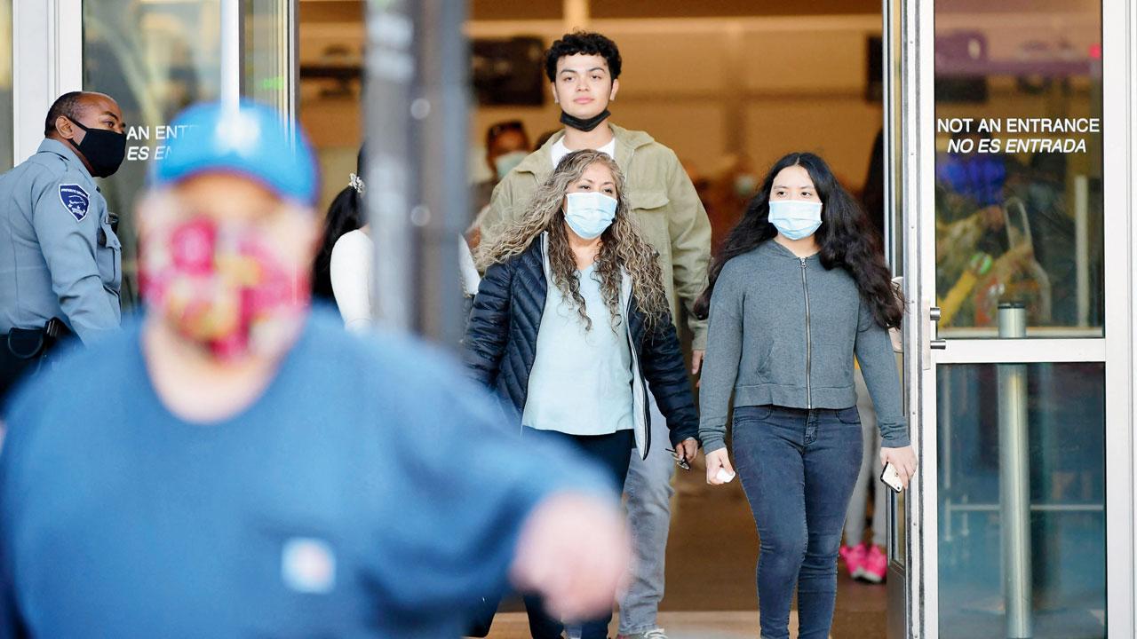 People wear facemasks upon entry into the US at the San Ysidro Land Port of Entry in San Ysidro, California, on November 7, a day before travel restrictions are lifted at the US-Mexico border