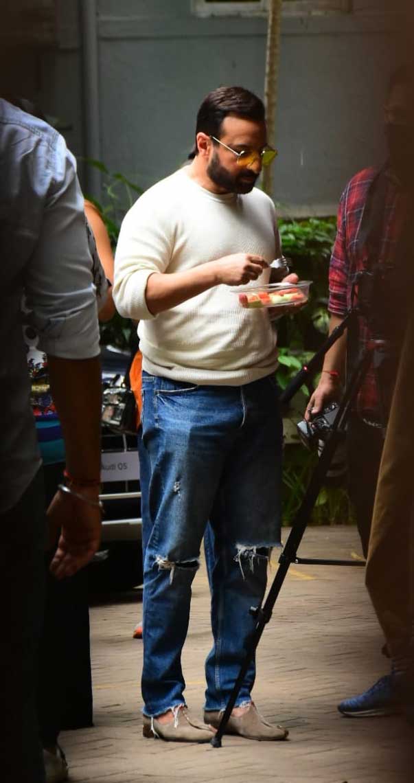 Saif wore a white tee with stressed denims. He was seen snacking in between the shots.