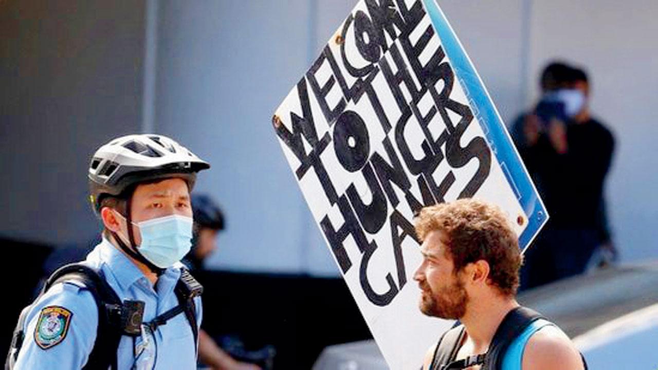 An Australian police officer stops an anti-masker at a rally. Pic/AFP