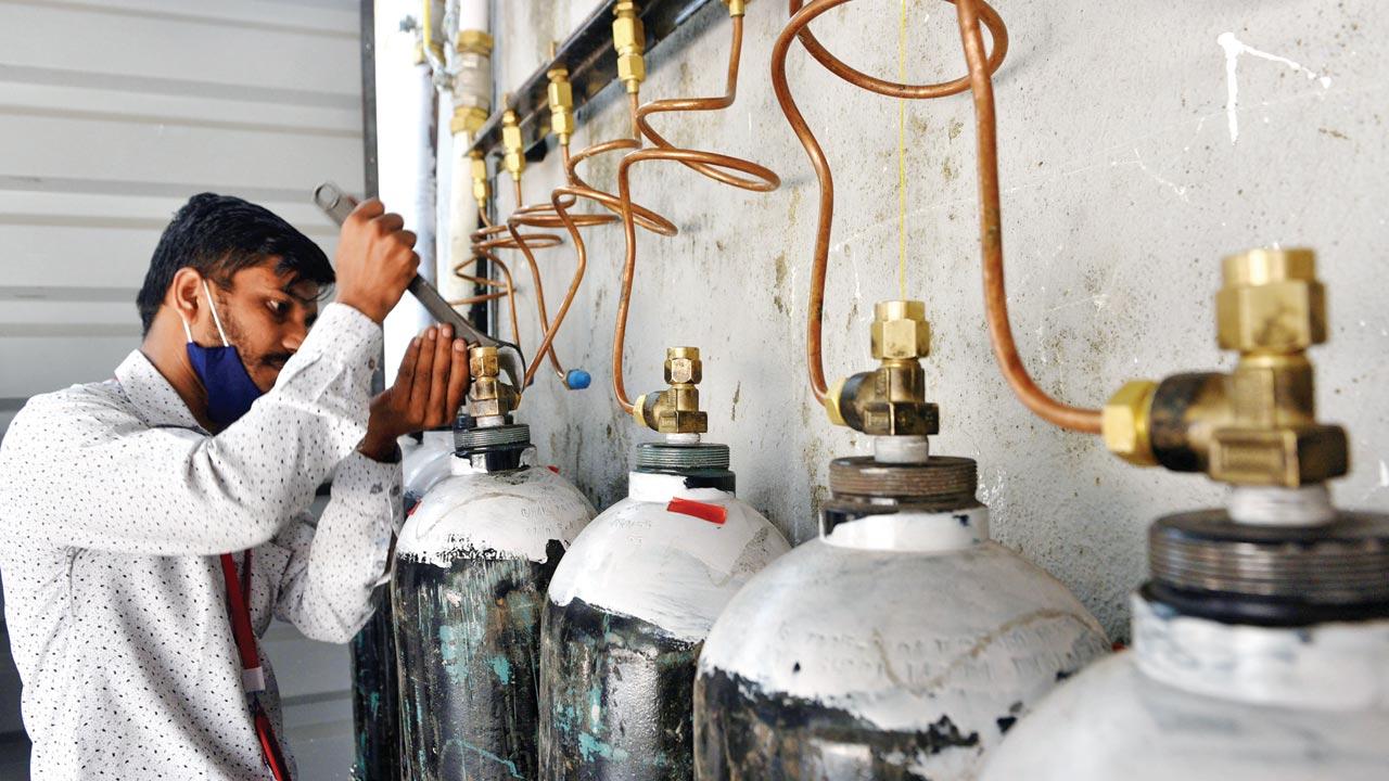 Workers connect a pipeline to oxygen cylinders at the NESCO Jumbo COVID Care Centre in Goregaon. File pic