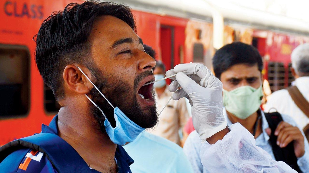 A health worker takes a swab sample from a passenger at Dadar on Sunday. Pic/Ashish Raje