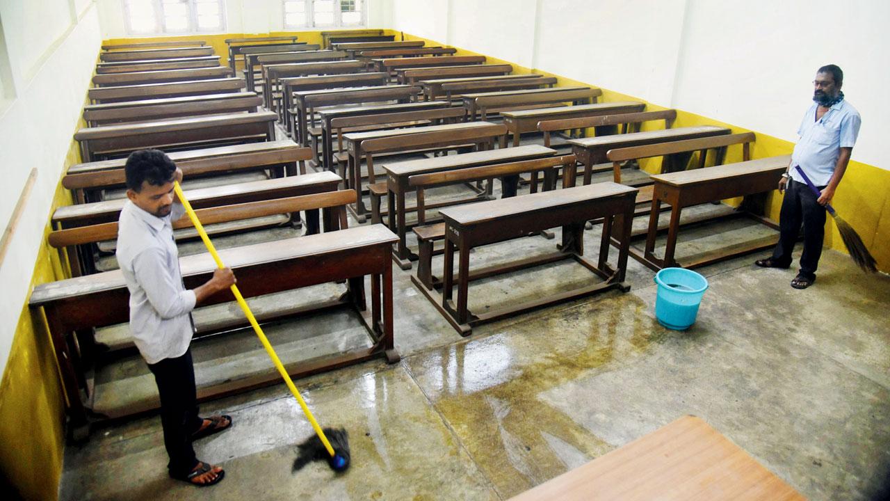 Workers clean a classroom at National College, Bandra West, on Tuesday. Pic/Sameer Markande