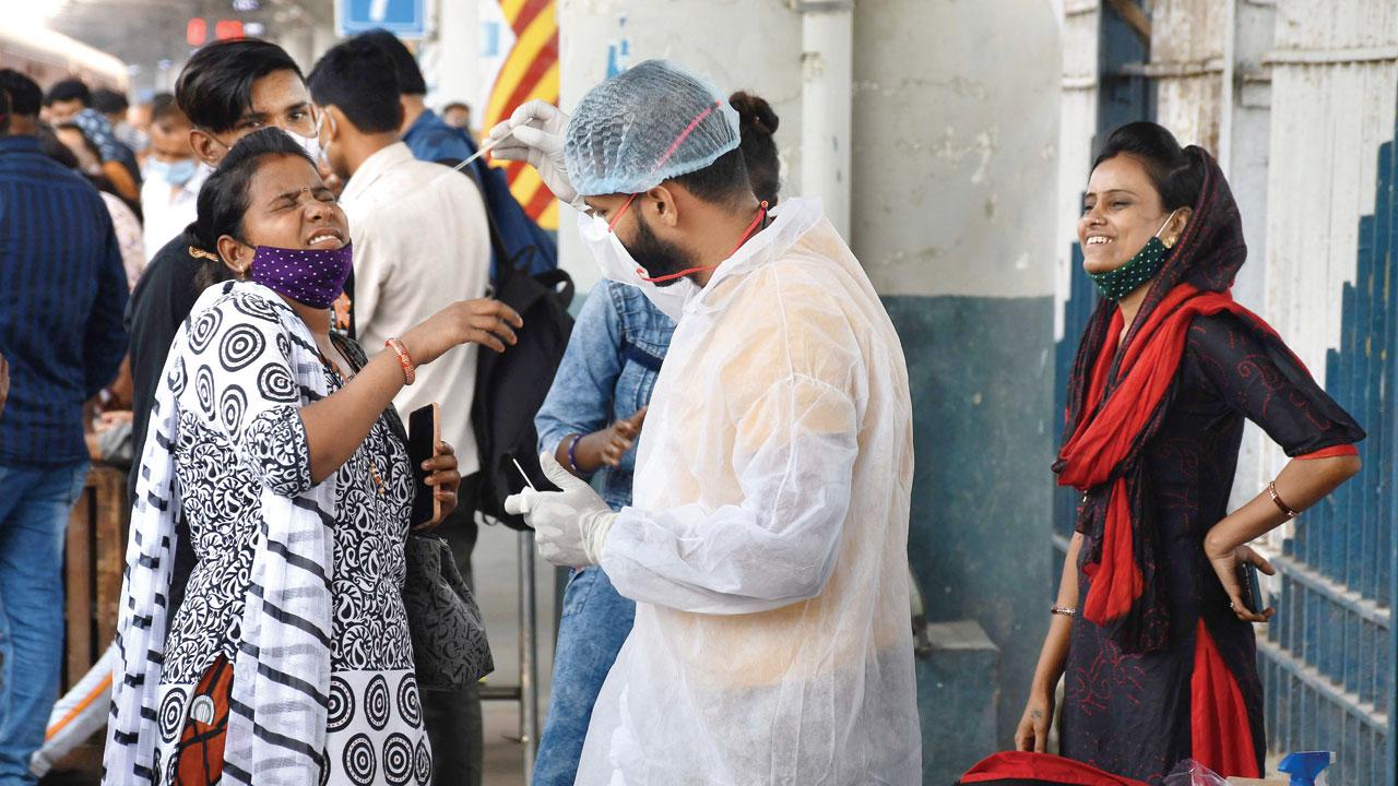 A BMC health worker tries to collect a swab sample of a woman who arrived aboard a Bhuj train, at Dadar station, on Sunday. Pic/Ashish Raje