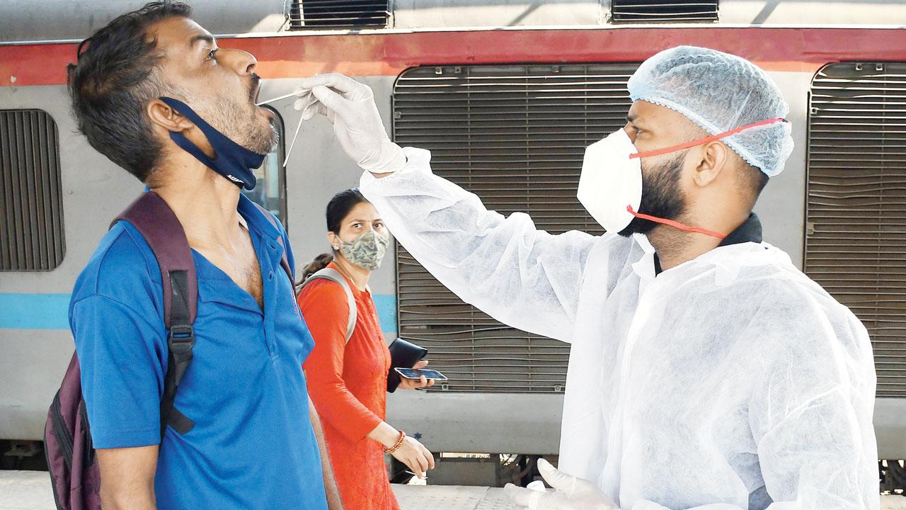 A BMC health worker takes a swab from a passenger at Dadar station on Thursday. Pic/Ashish Raje