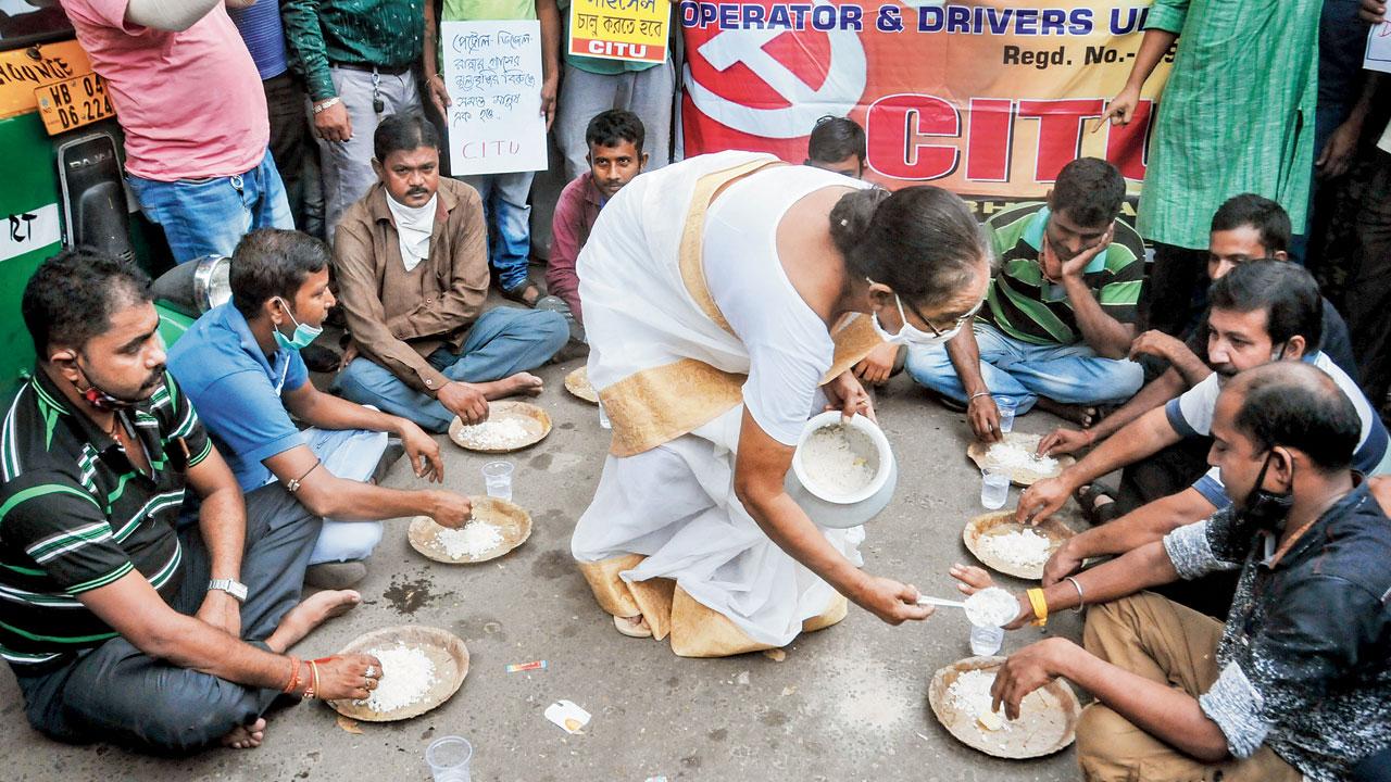 Ola-Uber cab operators and drivers affiliated to CITU Unions eat food on the road to protest the fuel price hike, in Kolkata, on Thursday