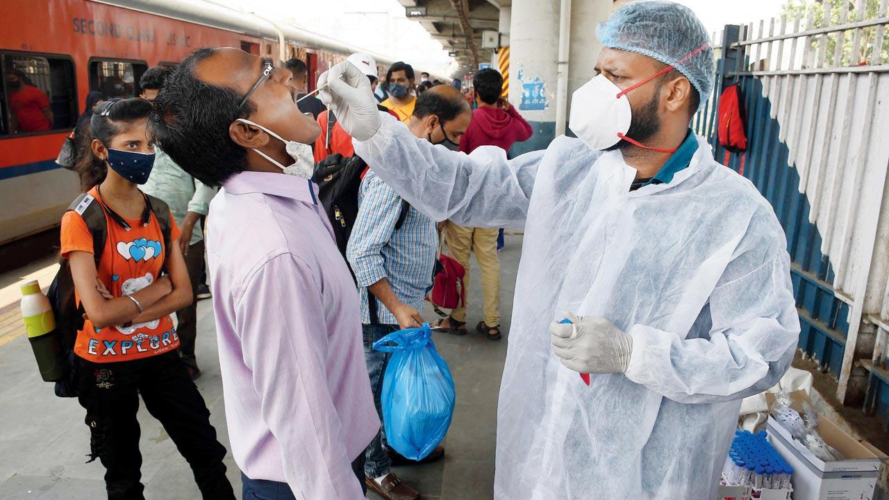 A civic health worker takes a throat swab of a passenger for COVID-19 test at Dadar station on Wednesday. Pic/Ashish Raje