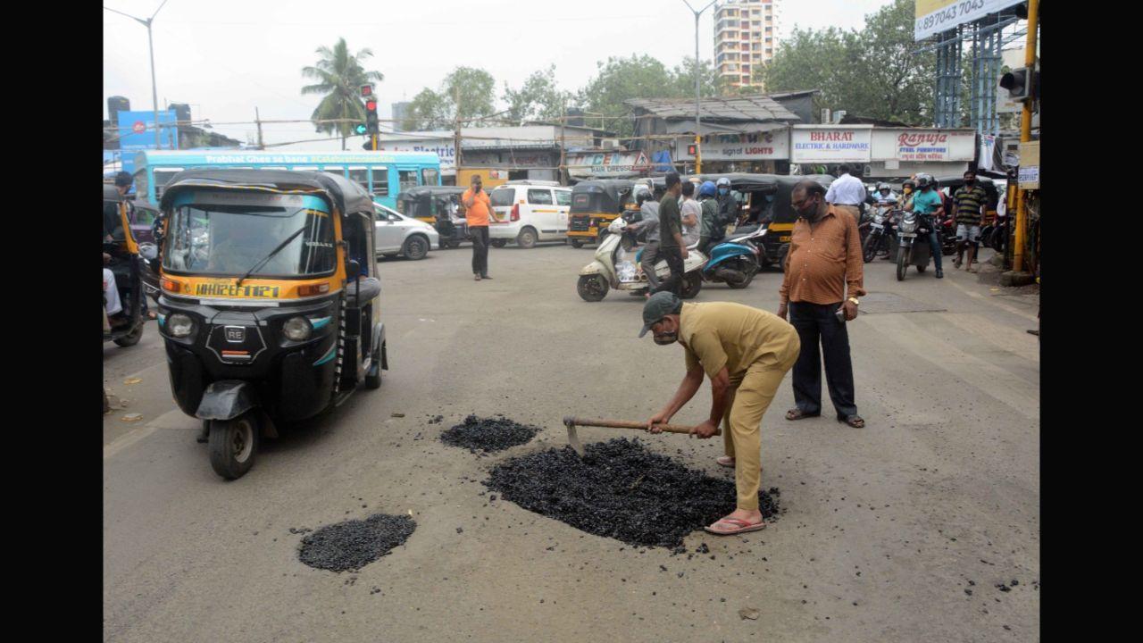 BMC worker filling pothole on Marve Road junction at SV Road, Malad in Mumbai.