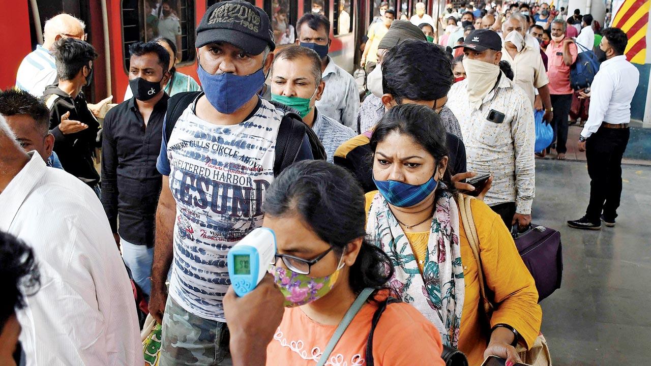 A woman undergoes COVID-19 health screening while other passengers wait for their turn on a platform at Dadar station, on Monday. Pic/Ashish Raje