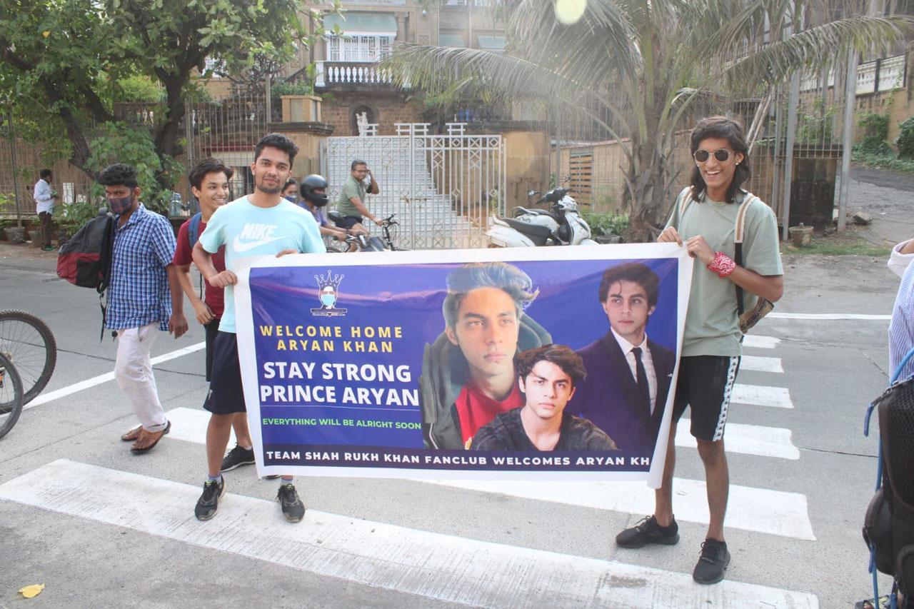 Seen here are two fans of Shah Rukh Khan (one of them, a Sanjay Dutt lookalike) holding a big banner in support of Aryan. 'Welcome home Aryan Khan', 'Stay strong Prince Aryan Everything will be alright soon', 'Team Shah Rukh Khan fanclub welcomes Aryan Khan' were the messages written on the banner.   