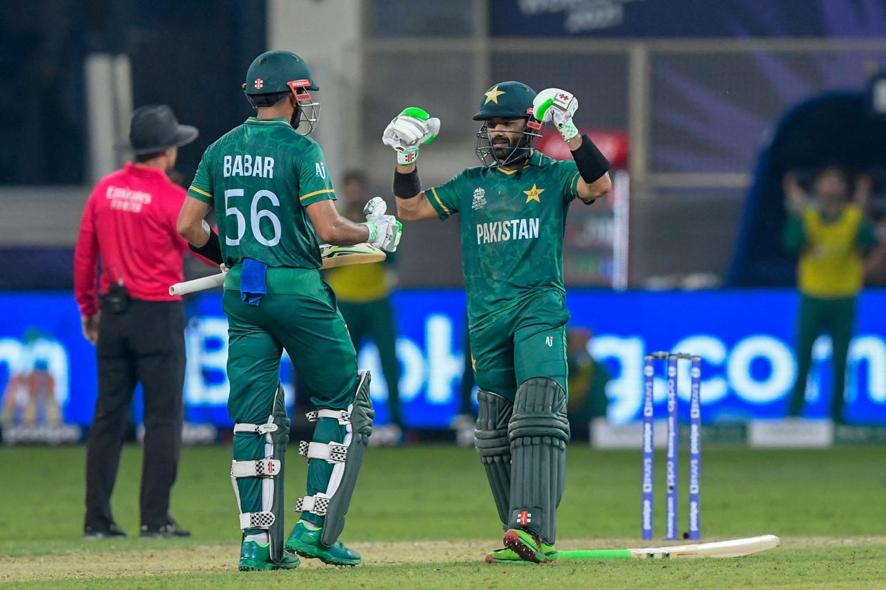 Pakistan's Mohammad Rizwan (R) celebrates after scoring a half-century (50 runs) as his team captain Babar Azam applauds