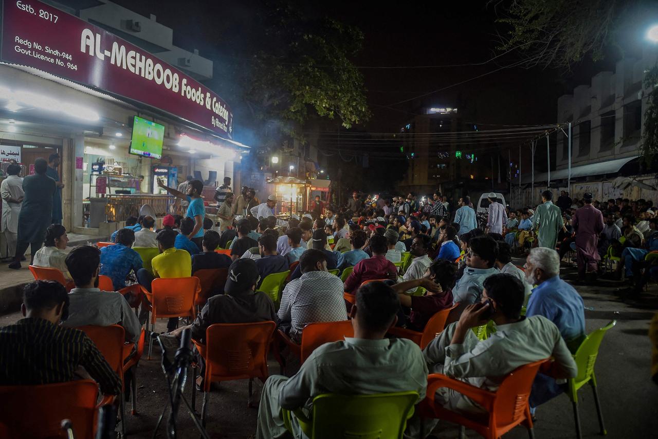 Cricket fans watch the live telecast of T20 cricket World Cup match between India and Pakistan happening in Dubai on a television installed at a restaurant in Karachi on October 24, 2021