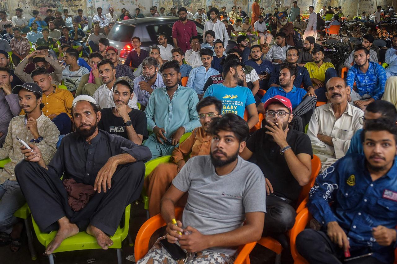 Cricket fans watch the live telecast of T20 cricket World Cup match between India and Pakistan happening in Dubai on a television installed at a restaurant in Karachi on October 24, 2021