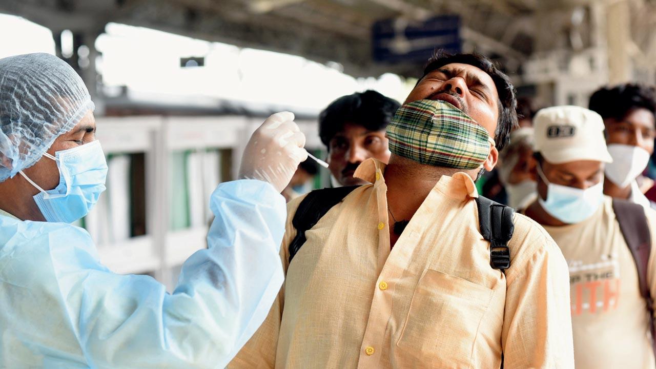 A health worker collects a swab sample of a passenger at the Lokmanya Tilak Terminus on Friday. Pic/Sameer Markande