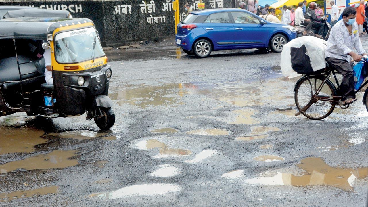 Commuters navigate potholes near Poisar Church at SV Road, Kandivli on Wednesday. Pic/Satej Shinde