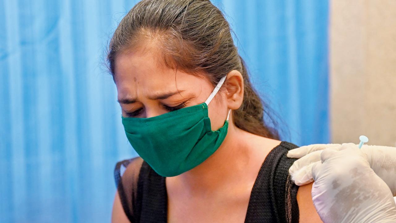 A woman reacts as she takes a jab of the vaccine in Mumbai. Pic/AFP