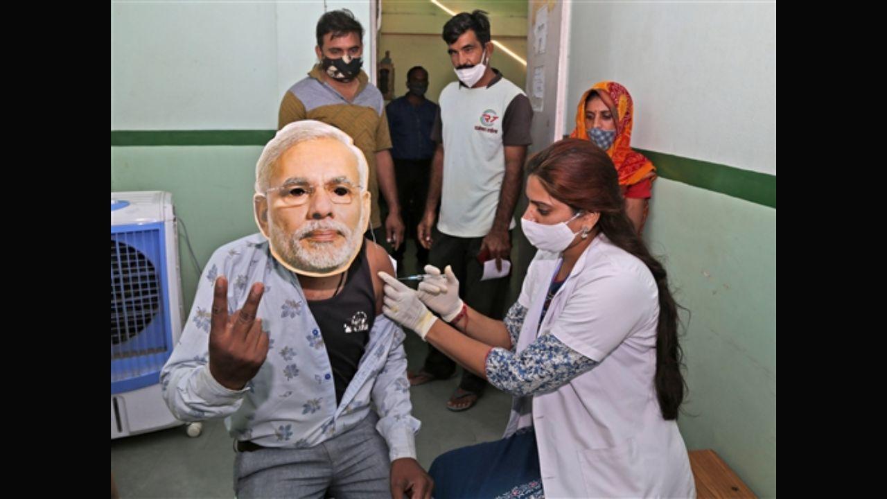A health worker inoculates a Covid-19 vaccine dose to a beneficiary wearing the face mask of PM Narendra Modi on PM's 71st birthday, during a mega-vaccination drive in Beawar, Rajasthan. Pic/PTI