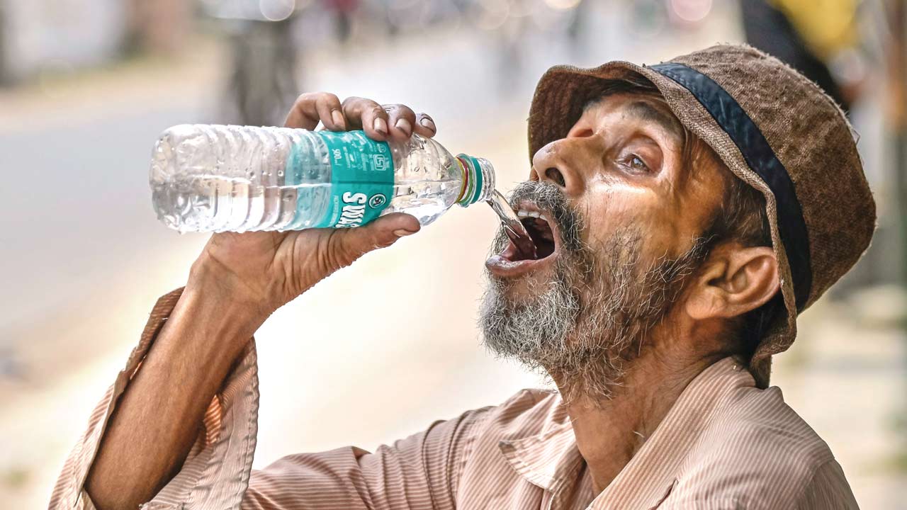 An elderly man quenches his thirst on a hot summer afternoon, in Nadia