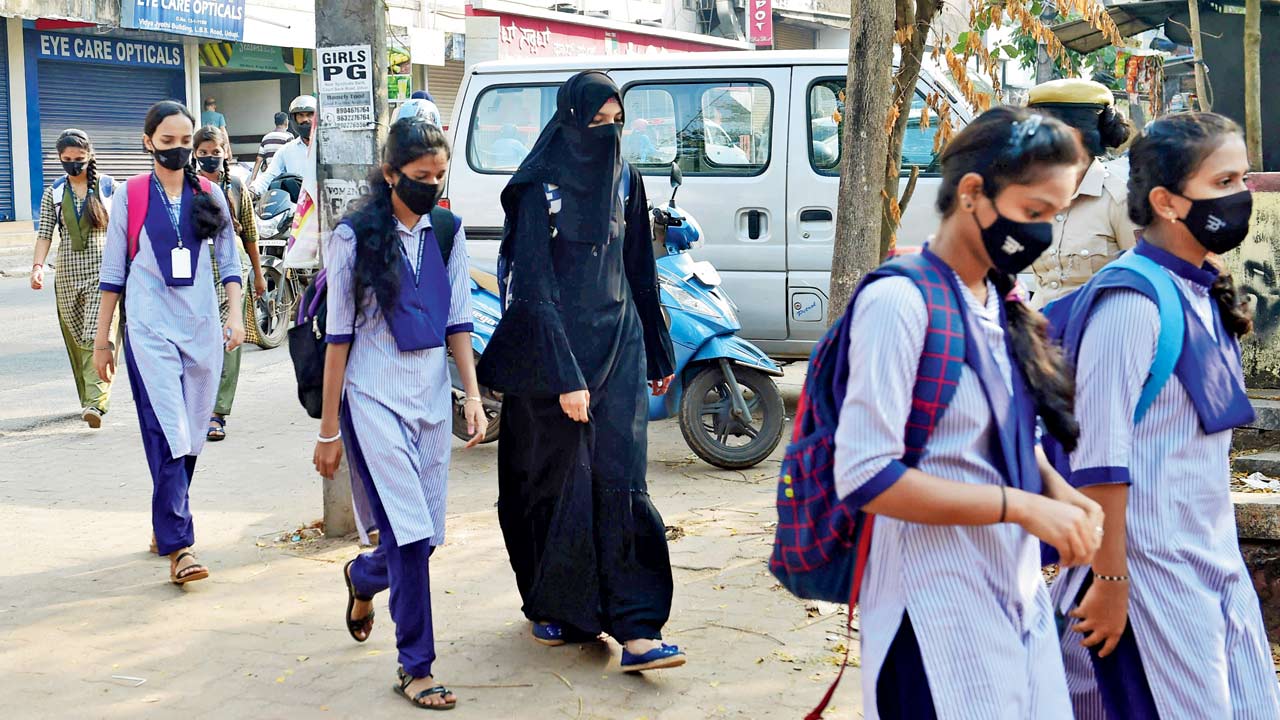 Hijab wearing schoolgirls arrive to attend their classes as a police woman stands guard outside a government girls school after the recent hijab ban, in Udupi, Karnataka. Udupi, says journalist Greeshma Kuthar, “is like Nagpur of Maharashtra [where the RSS headquarters is based]”. Pic/Getty Images
