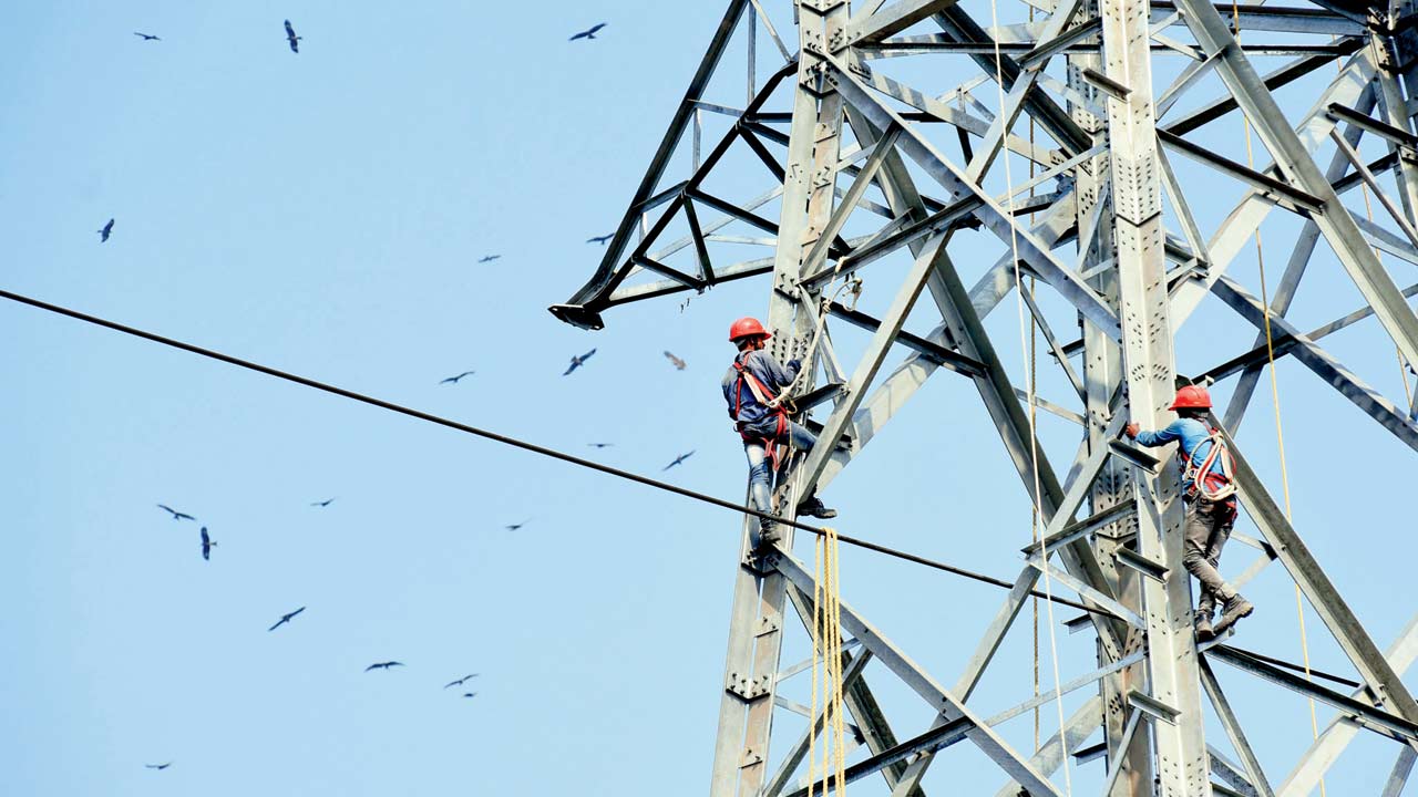 Two men at work on a high-voltage electricity pole, at Kanjurmarg. File pic/Sameer Markande