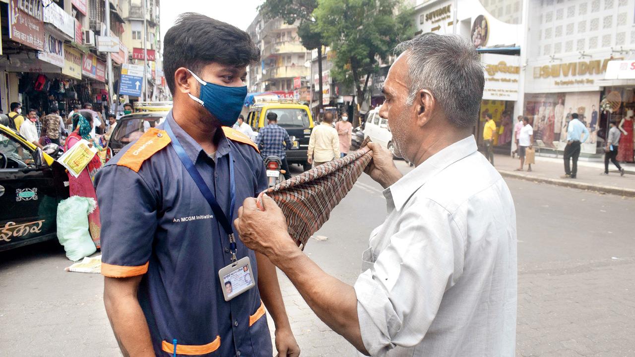 A mask marshall fines a citizen for not wearing a mask in October 2020. File pic