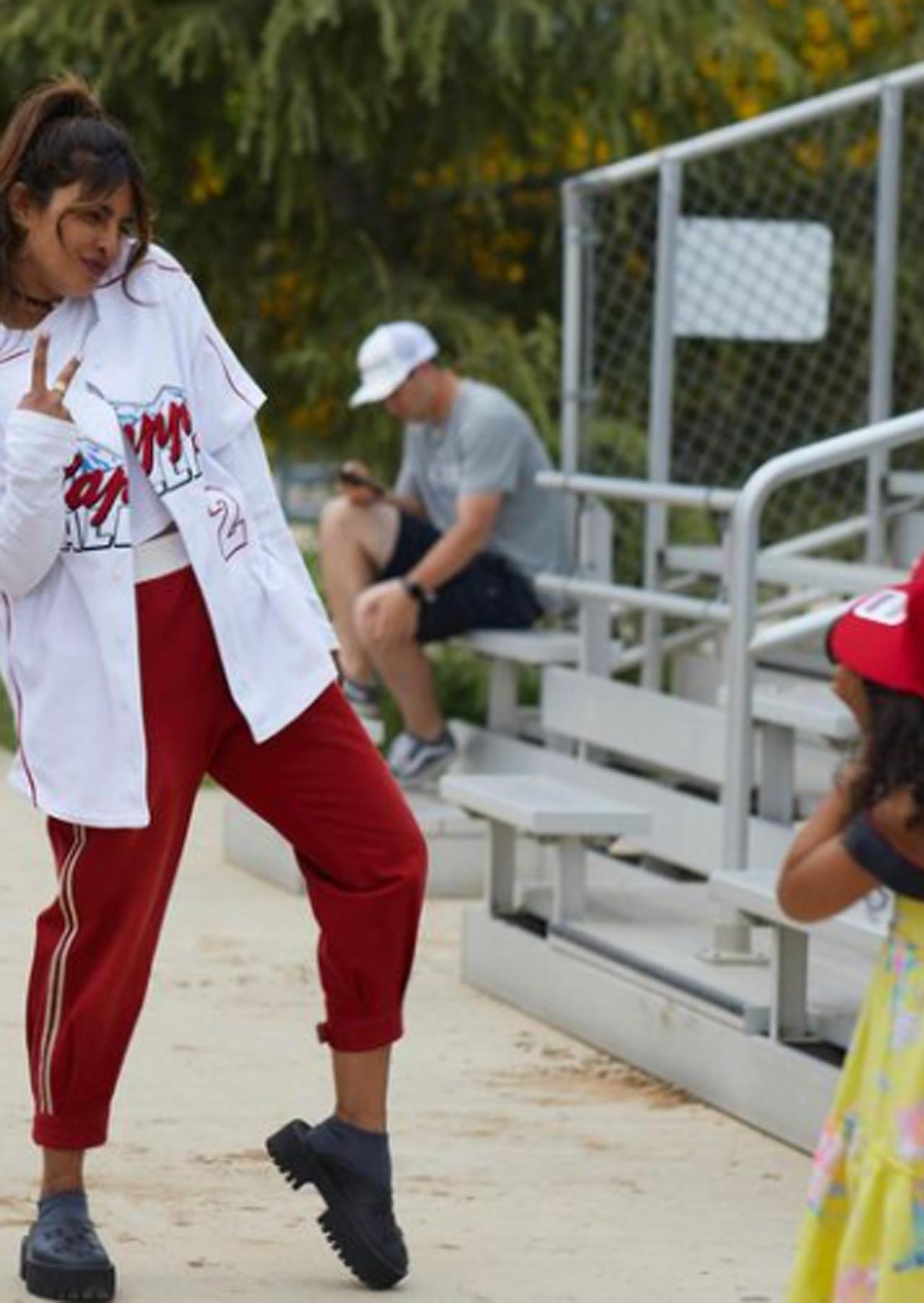 For the game day, she chose to wear a long oversized white jersey with her name written on it and rust coloured pants. She kept her hair tied in a ponytail. In this particular candid and cute moment, the actress posed rather amusingly as a little girl tried to capture her. The girl in question is her cousin Divya Jyoti's daughter.