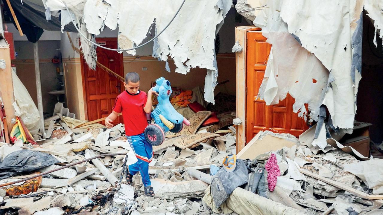 A Palestinian boy salvages a toy from his house in Rafah Monday. Pics/AP, AFP