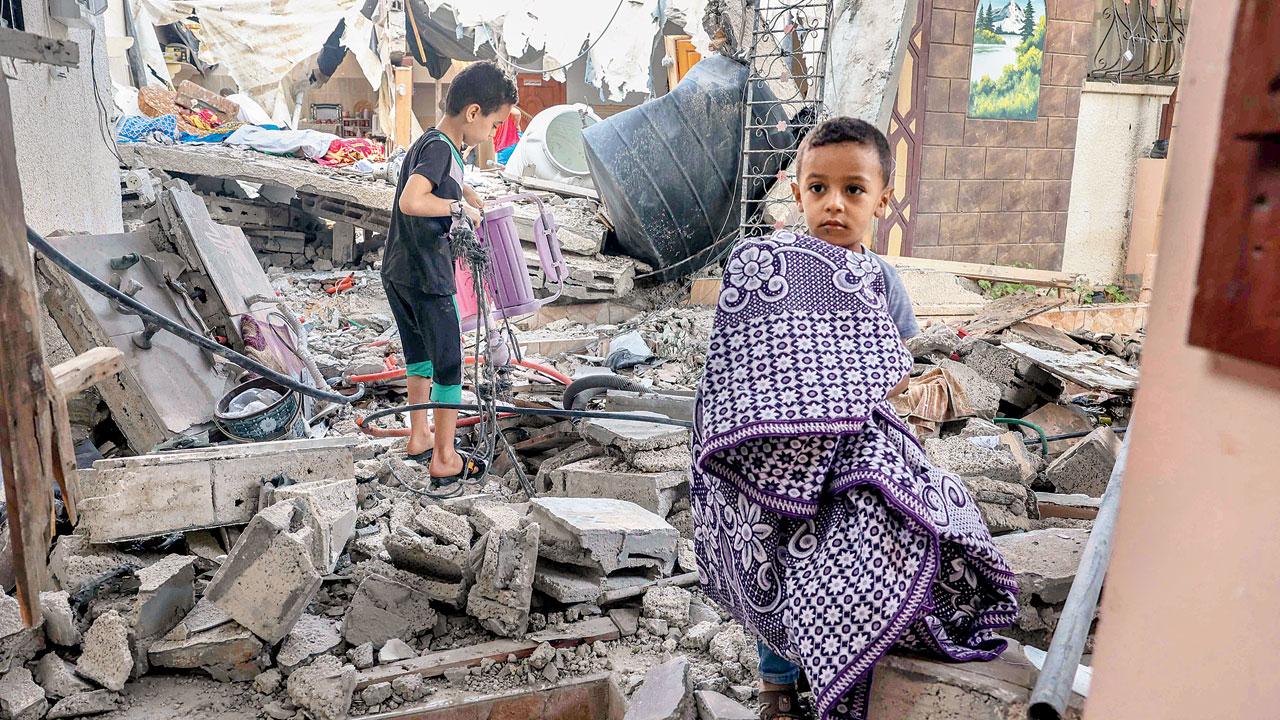 Palestinian boys salvage belongings from their house which was destroyed during the past three days of conflict with Israel in Rafah in Gaza, Monday. PIC/AFP