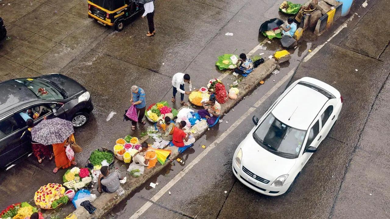 Flower party: The heavy showers didn’t discourage hawkers from selling flowers on a traffic divider outside Borivli station. Pic/Shadab Khan