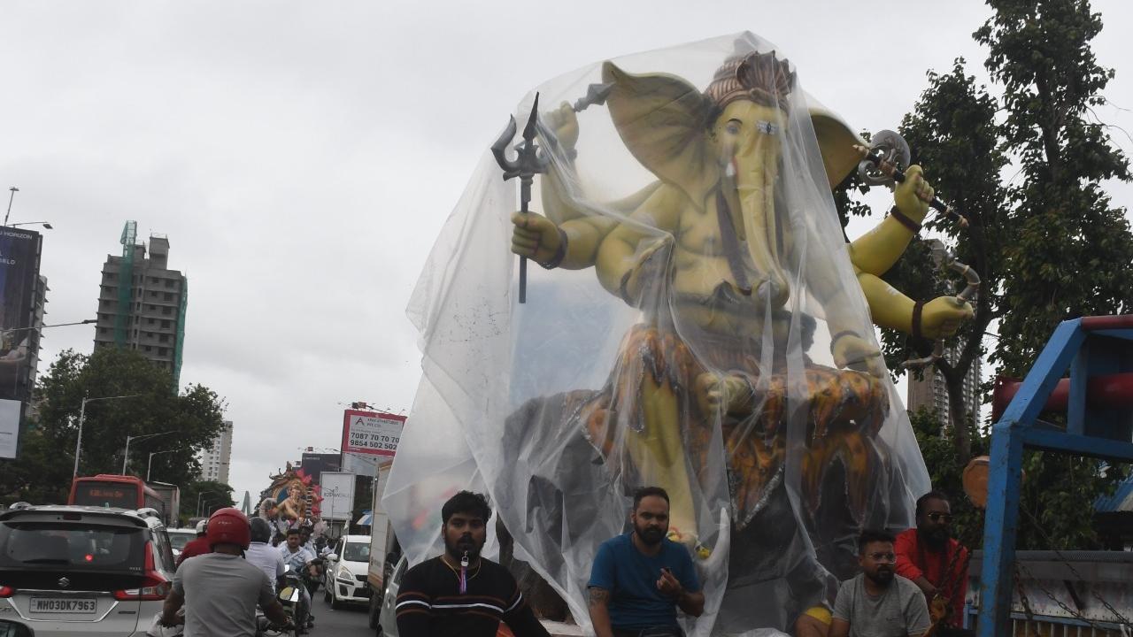 Devotees cover up the Ganpati idol with a plastic sheet to protect it from rain. Pic/Ashish Raje