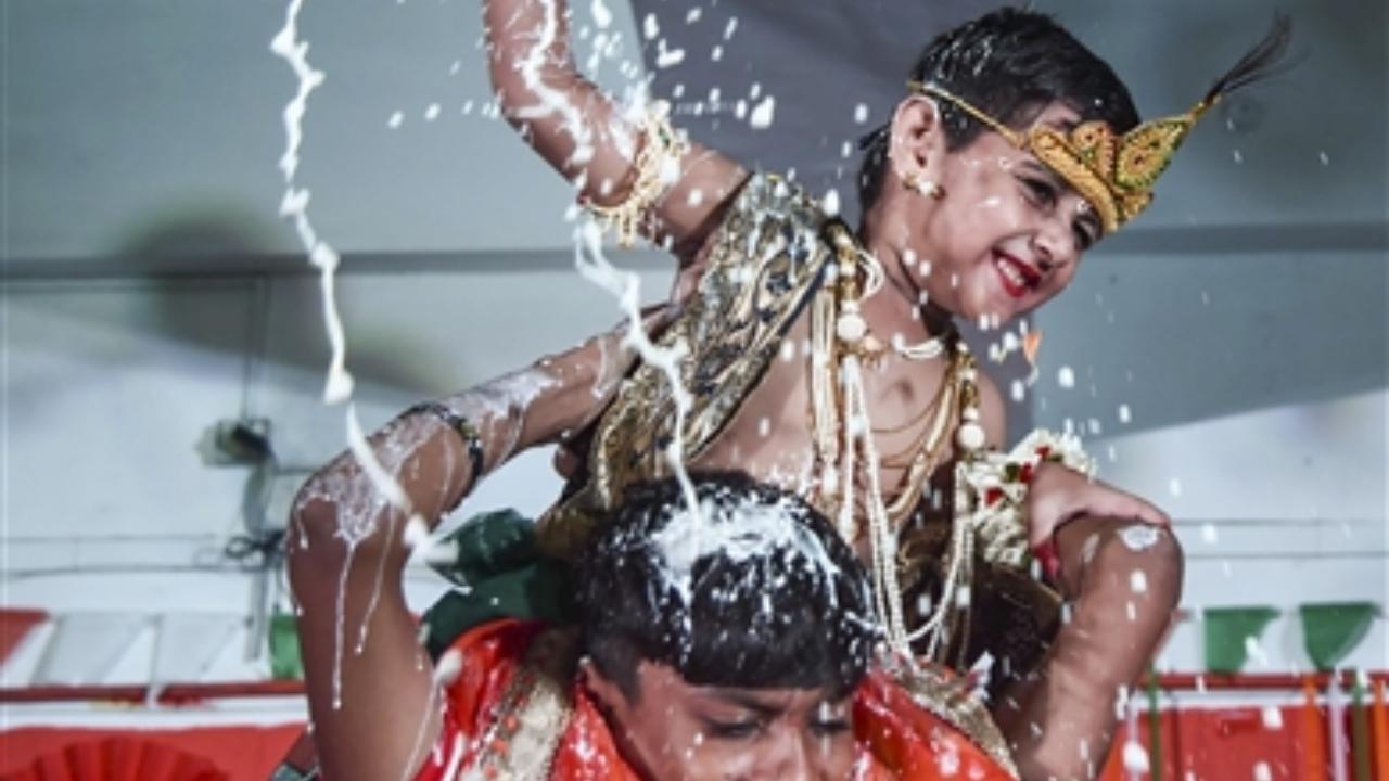 A student dressed as Lord Krishna breaks the 'dahi handi' during 'Janmashtami' festival celebrations at New Bombay City School in Navi Mumbai