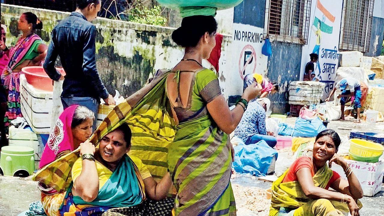 A fisherwoman takes the cover of her friend’s saree to beat the heat at Sassoon Dock, Colaba, on Sunday. Pic/Shadab Khan
 