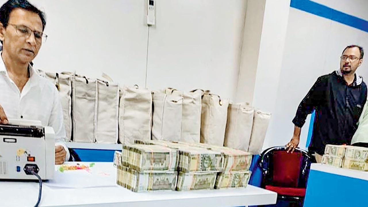Officials count the cash seized during the raids, on Thursday