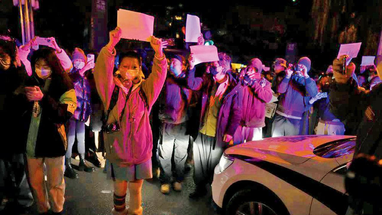 Protesters hold up blank papers and chant slogans as they march in protest in Beijing against strict Covid restrictions in China. Pic/AP
