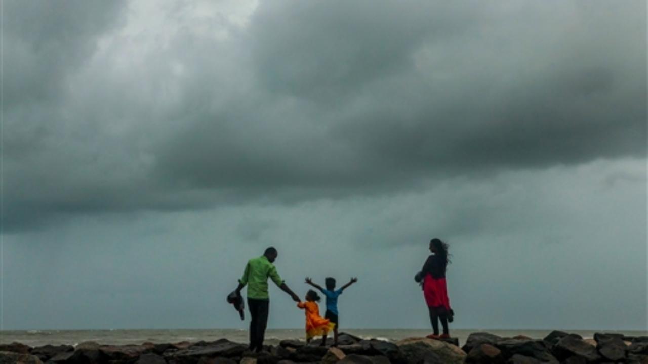 A family visits the sea-shore ahead of the landfall of the cyclone Mandous, in Chennai