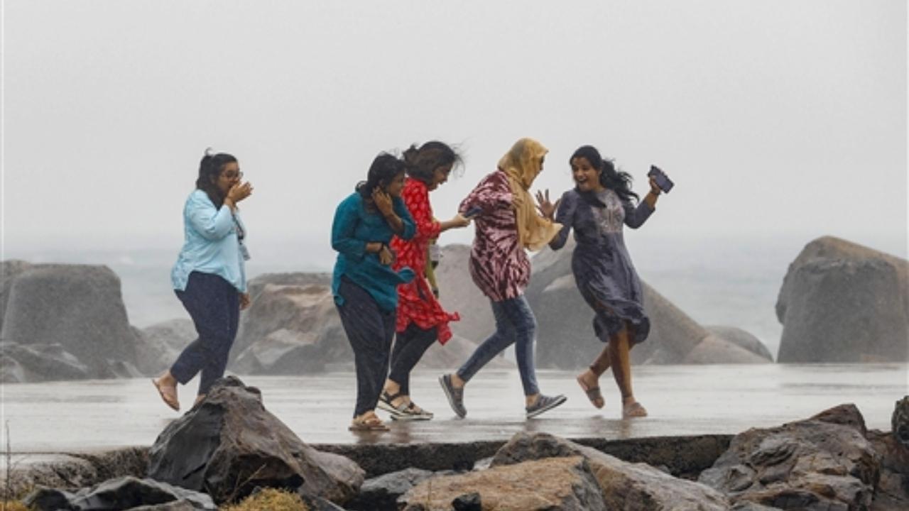 Young women react as sea waves crash at the sea-shore in Chennai