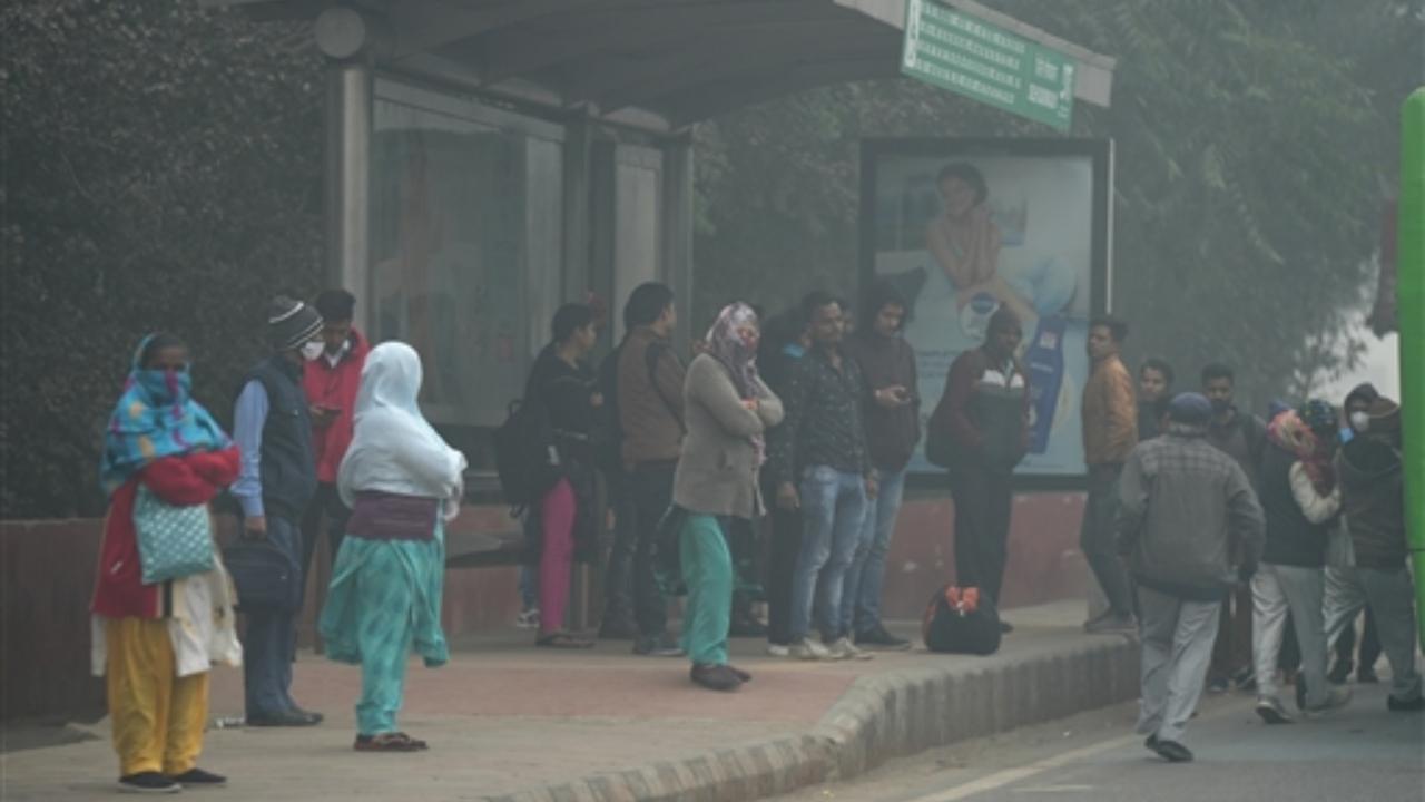 On Tuesday, commuters wait to board a bus amid dense fog during a cold winter morning, at a bus stand in New Delhi