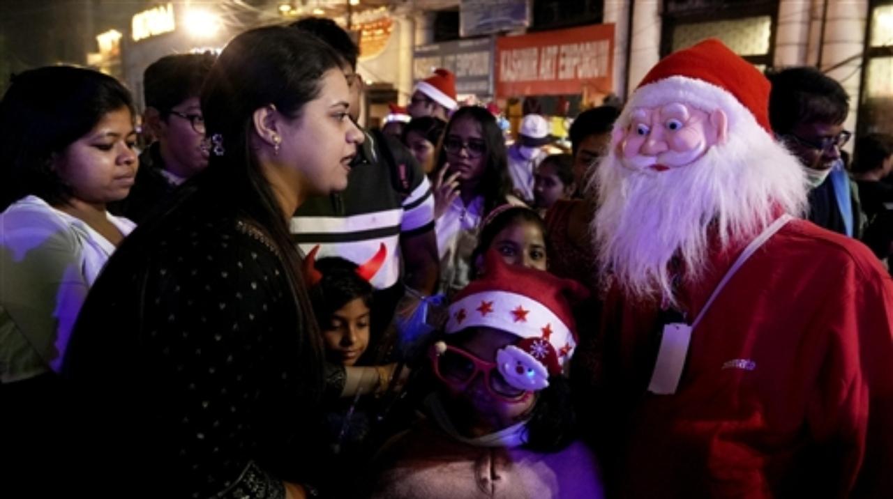 A man dressed as Santa Claus interacts with people at Park Street on the eve of Christmas Day celebrations, in Kolkata
