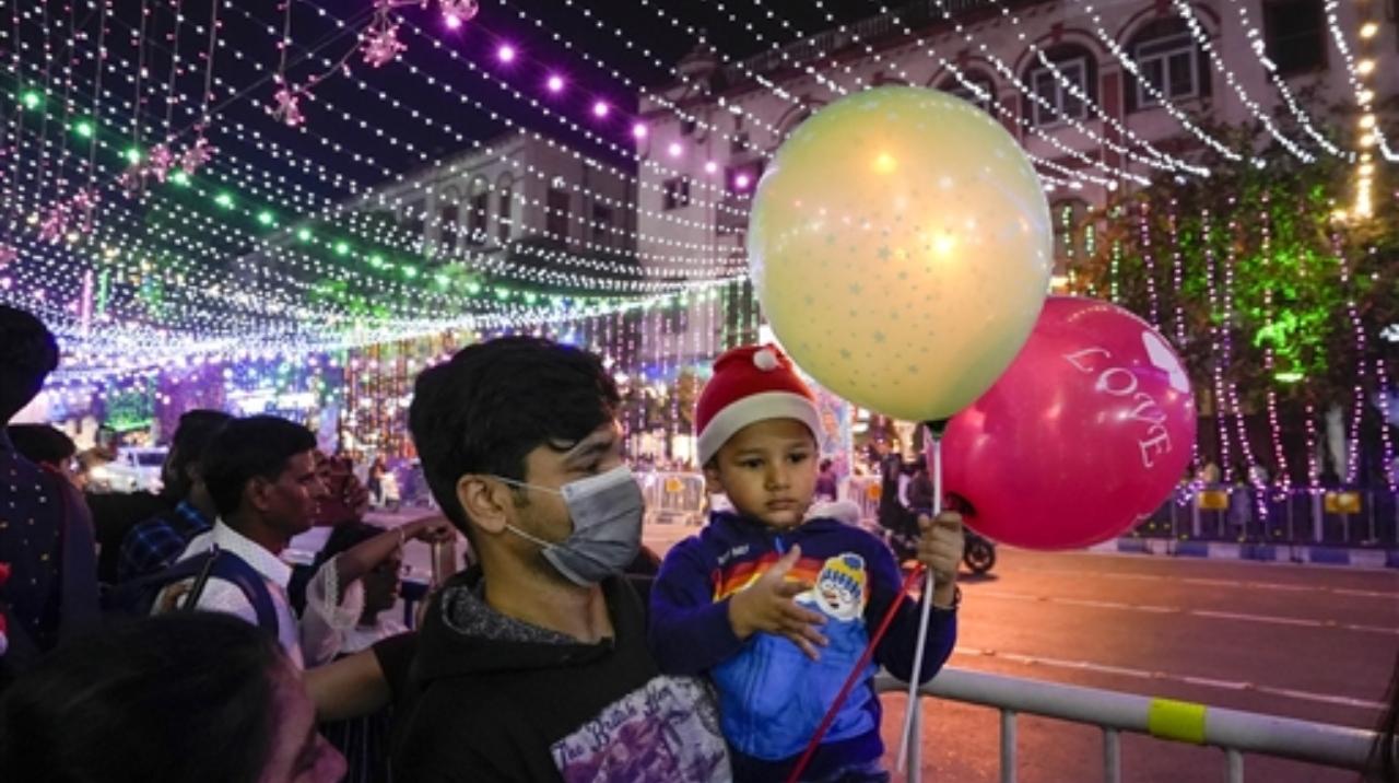 A visitor wearing face mask carries his child, amid rising COVID-19 cases in some countries, at illuminated Park Street
